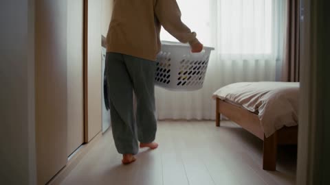 女子端着洗衣篮穿过卧室