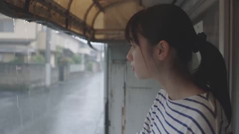日本公交站避雨的年轻女子望向雨中